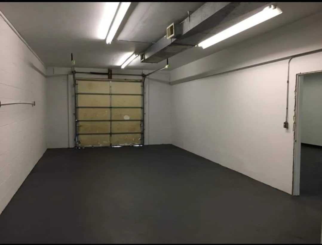 The same commercial space after a garage floor renovation, featuring a smooth, dark grey protective floor coating and painted white walls.