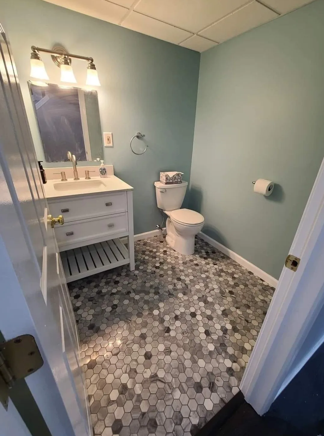 A completed renovation showing the bathroom remodel results with green walls and hex tile.