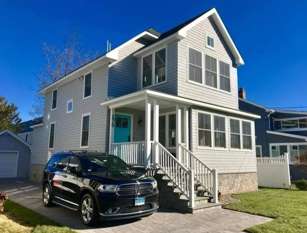 Two-story gray home showcasing a recent exterior house painting with a bright turquoise front door.