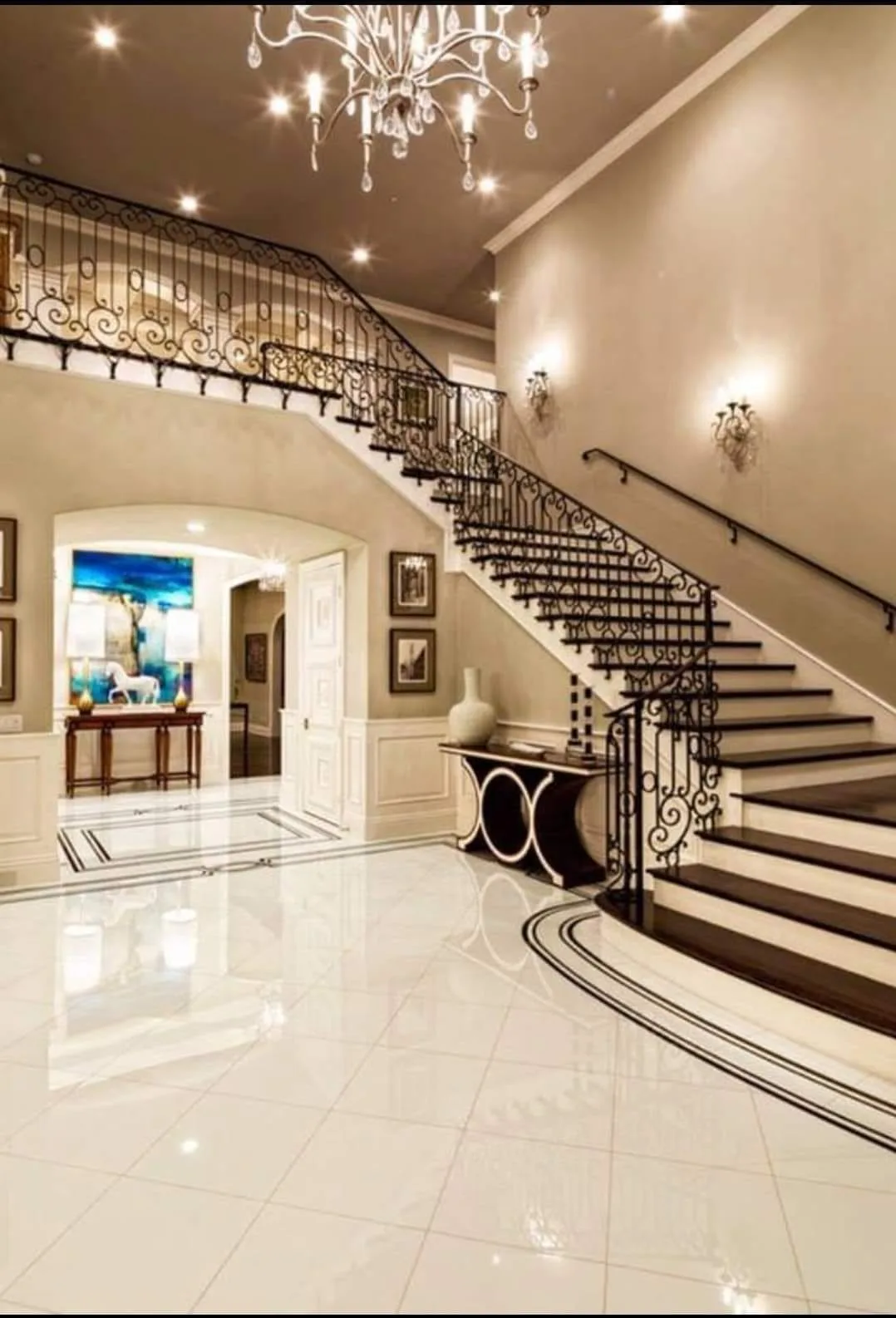 Completed interior painting project in a luxury home entryway with a grand staircase and chandelier.
