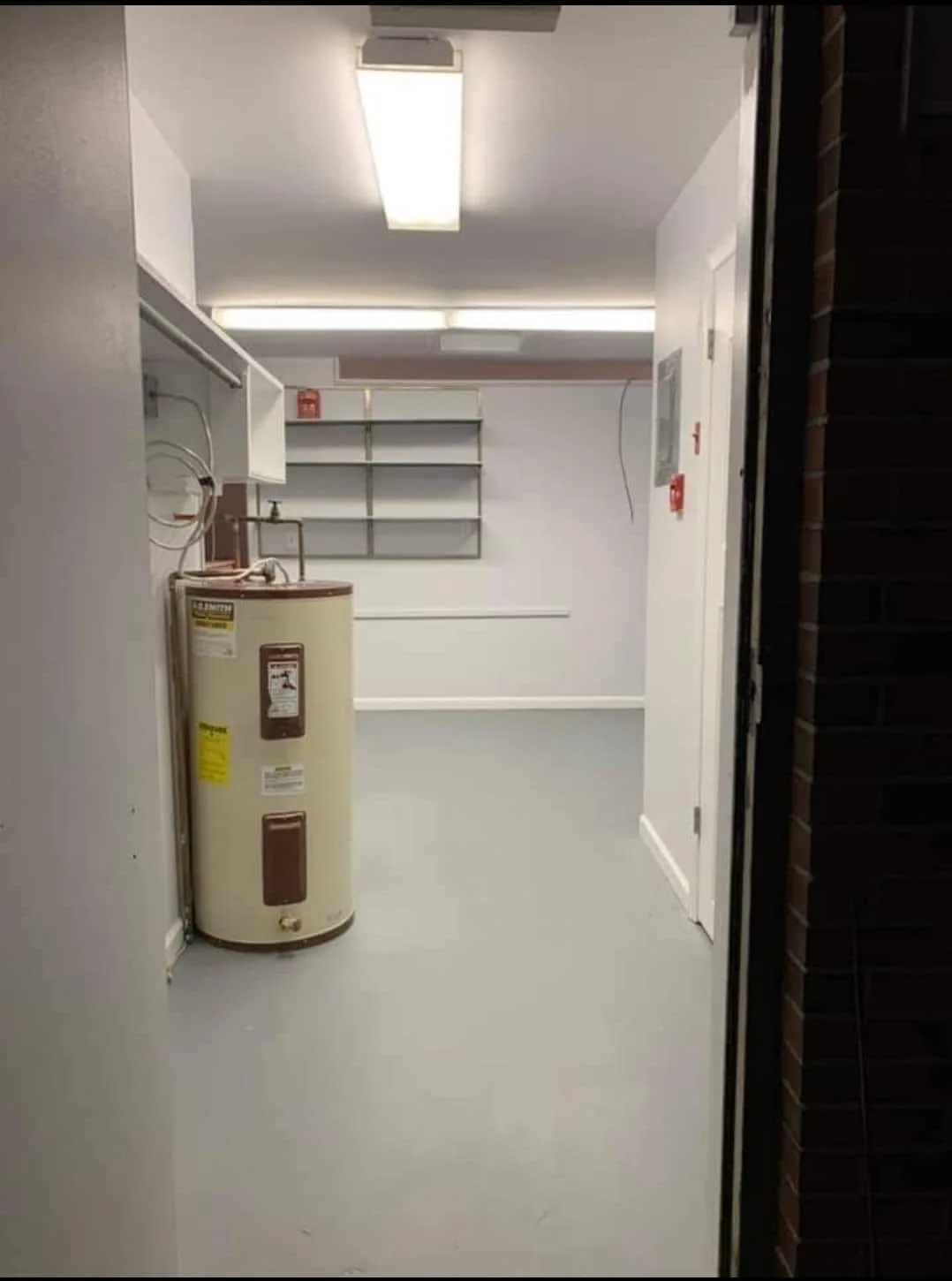 After photo of a finished commercial utility unit showing clean painted walls and a new floor as part of a comprehensive utility space renovation.